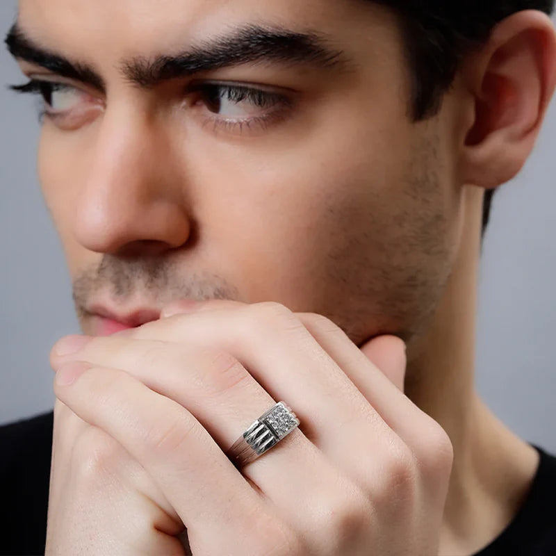 Close-up of a man wearing a silver ring with a diamond, against a neutral background.