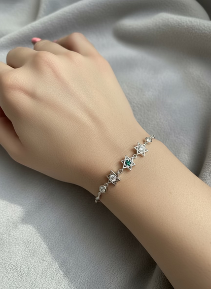 Hand wearing a silver bracelet with star designs on a light gray fabric background